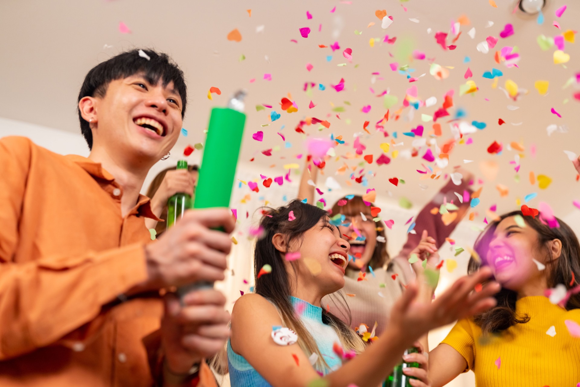 Group of Young Asian people celebration holiday party and playing confetti together in living room.